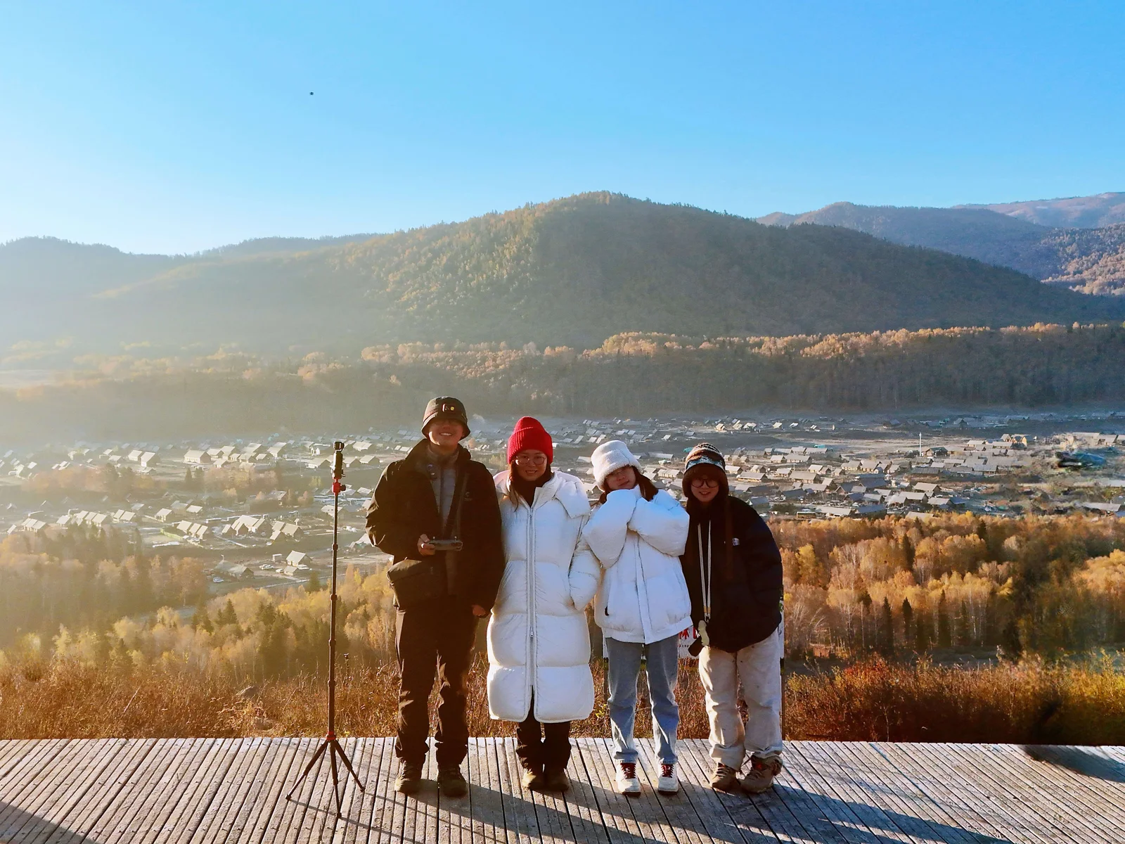 阳光下的户外旅行合影，远处是山林和村落